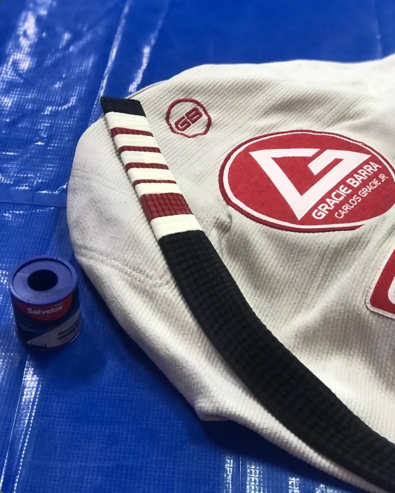 Kimono Gracie Barra com faixa preta dobrada sobre o tatame